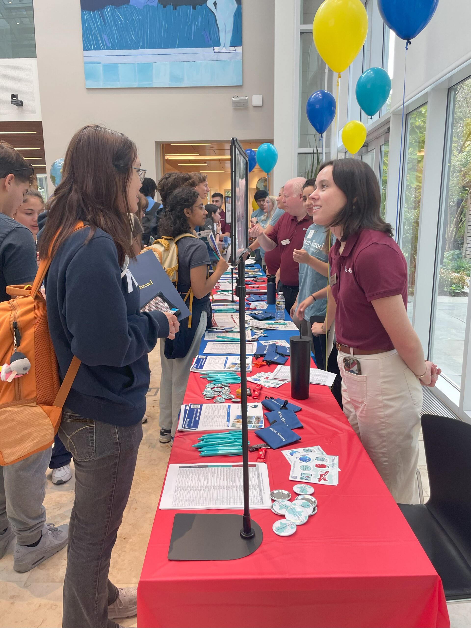 Staff member talking to a student in Perry World House at the Penn Abroad Fair 2024