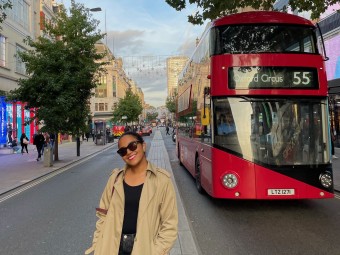 Student posing in front of red double-decker bus
