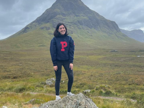 Student standing on a rock in front of a large mountain in Scotland