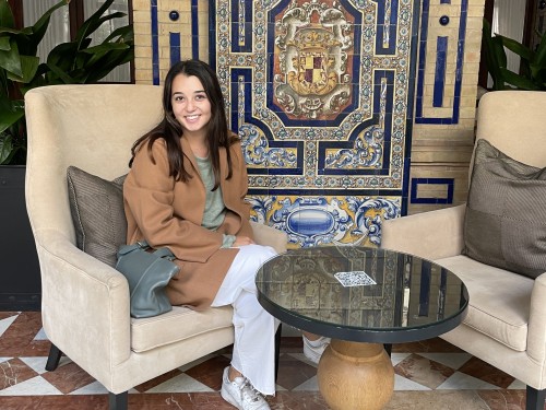Student sitting in hotel lobby in front of decorative Spanish crest mosaic