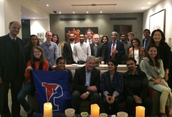 Nearly two dozen people are gathered together, holding a Penn flag, at an event with UPIASI. 