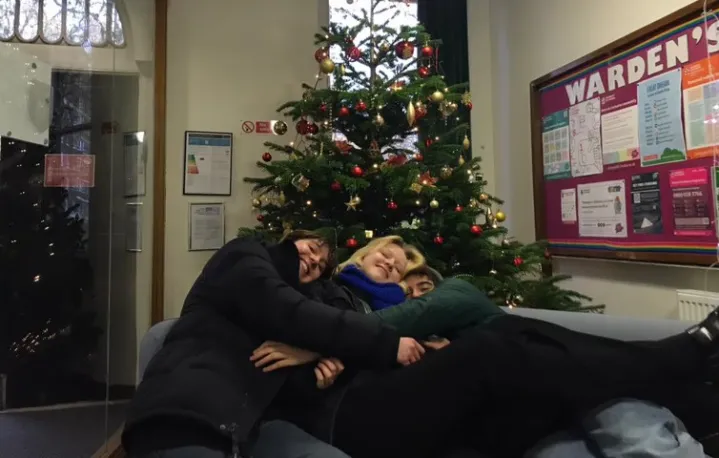 Students embracing in front of a Christmas tree