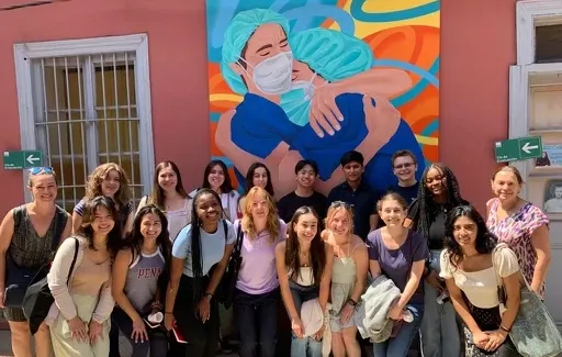 Student group photo in front of mural of nurses holding each other