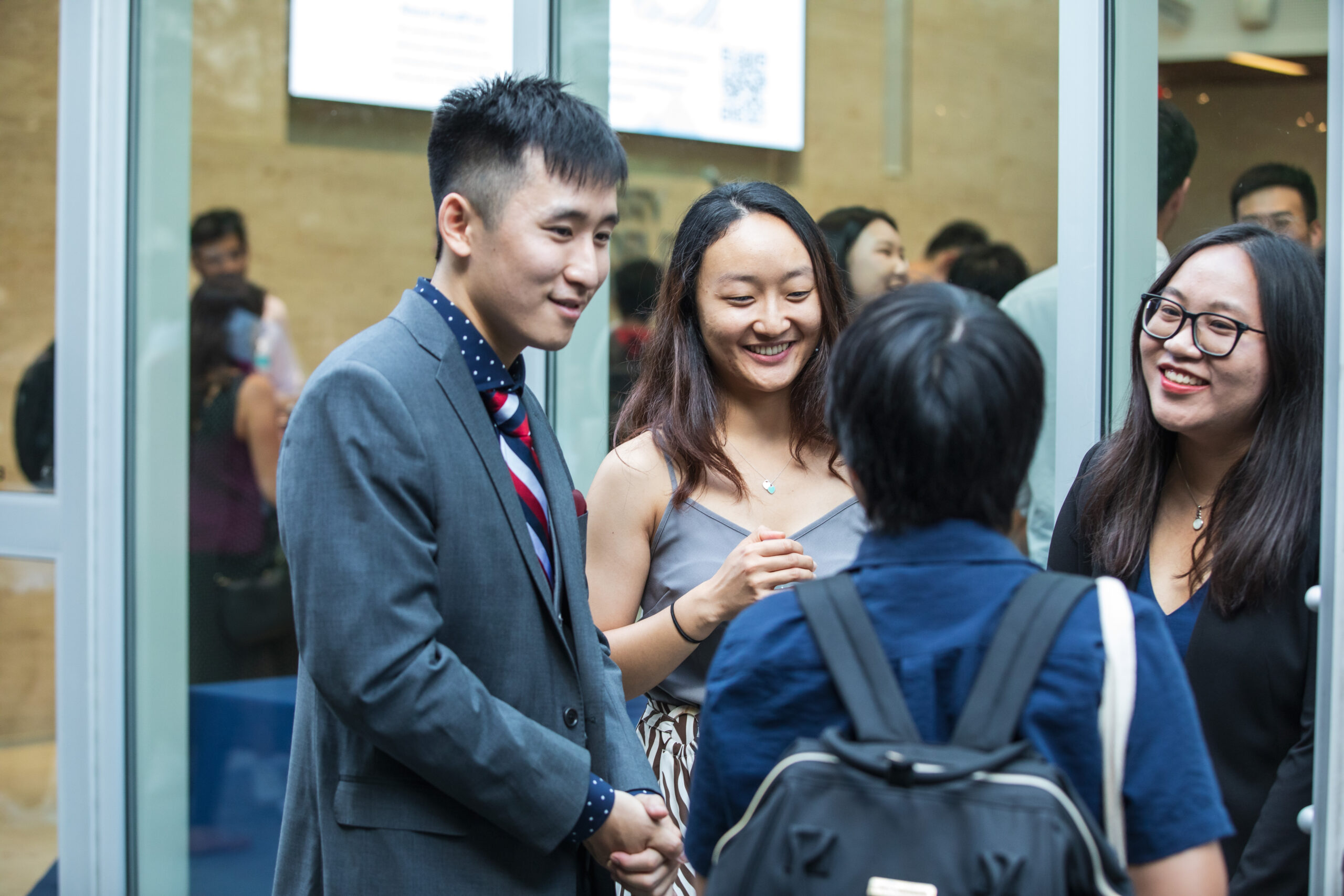 Four students huddled together outside during a reception talking